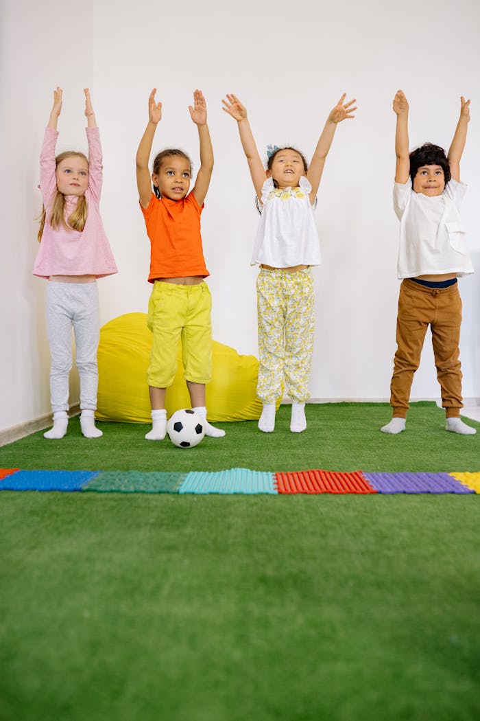 A cheerful group of diverse children enjoying playtime indoors, raising their hands joyfully.